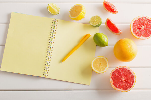 Цитрусовые с ноутбуком на белом деревянном столе
