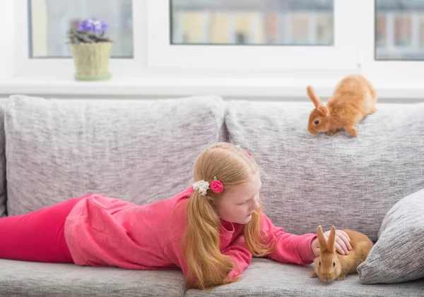 Улыбающаяся девушка с двумя кроликами в помещении — стоковое фото
