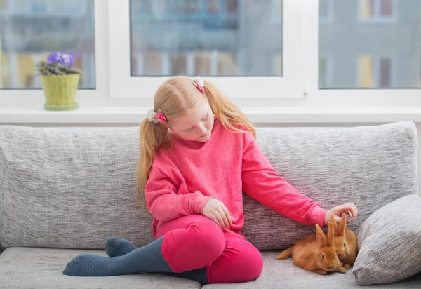 Menina sorridente com dois coelhos em casa — Fotografia de Stock