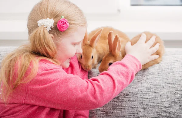 Chica sonriente con dos conejos de interior —  Fotos de Stock