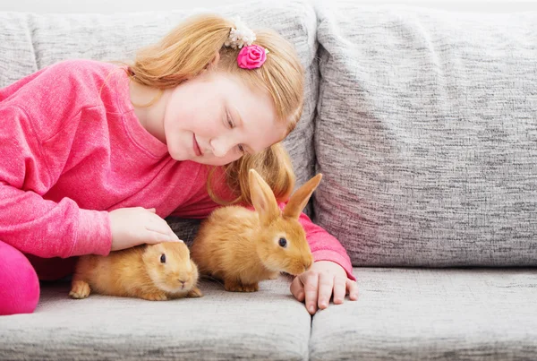 Sorridente ragazza con due conigli al coperto — Foto Stock