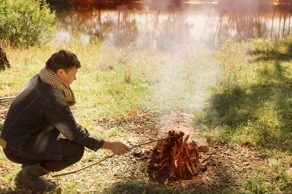 Mature man sitting at campfire — Stock Photo, Image