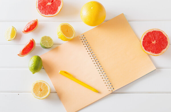 Цитрусовые с ноутбуком на белом деревянном столе
