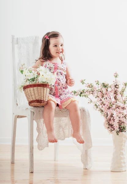 Happy little girl with flowers indoor — Stock Photo, Image