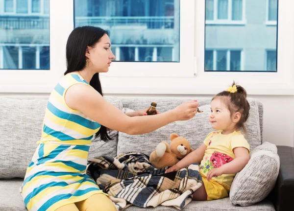 Mother pouring tasty syrup to ease her little girl's cough — Stock Photo, Image