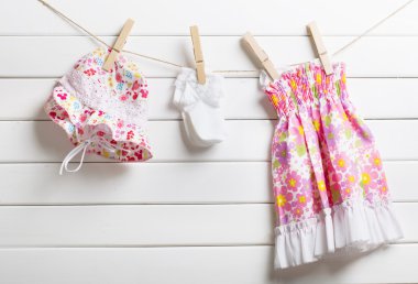 Clothesline üzerinde ahşap arka plan asılı bebek giysileri