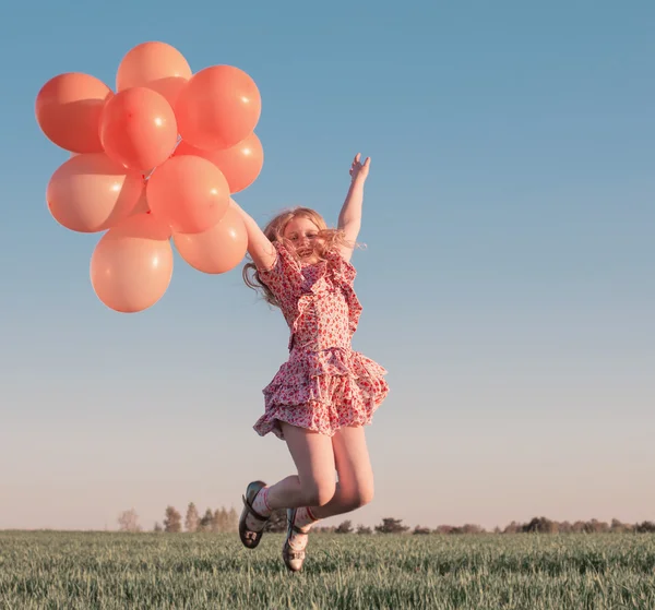Menina feliz com balões laranja ao ar livre — Fotografia de Stock