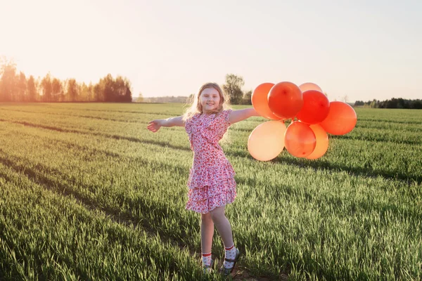 Menina feliz com balões laranja ao ar livre — Fotografia de Stock