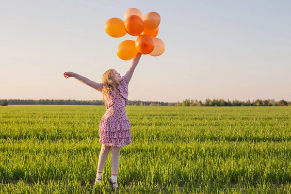 Šťastná dívka s venkovní oranžové balónky — Stock fotografie