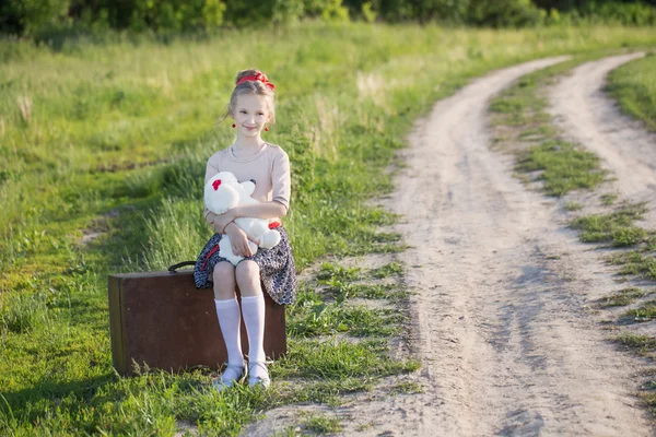 Beautiful girl on suitcase with toy outdoor — Stock Photo, Image
