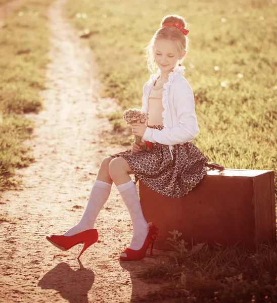 Bella ragazza sulla valigia con fiori all'aperto — Foto Stock