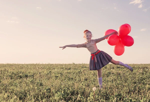 Šťastná dívka s červenými balóny venkovní — Stock fotografie