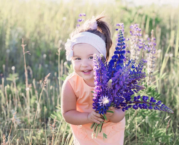 Liten flicka med blommor utomhus — Stockfoto