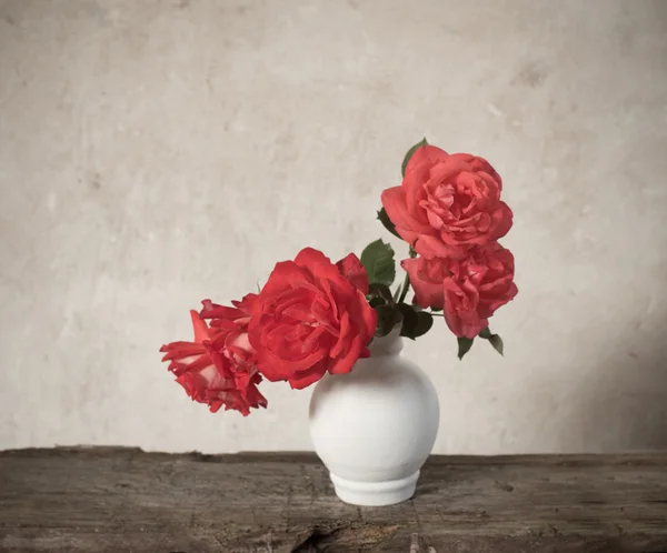 Rosas vermelhas na velha mesa de madeira — Fotografia de Stock