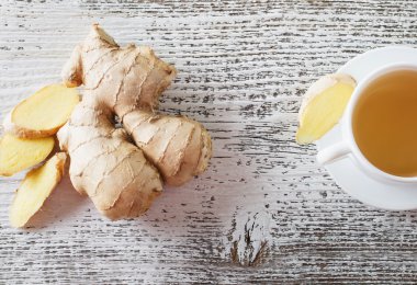 Ahşap arka plan üzerinde beyaz bir fincan çay zencefil