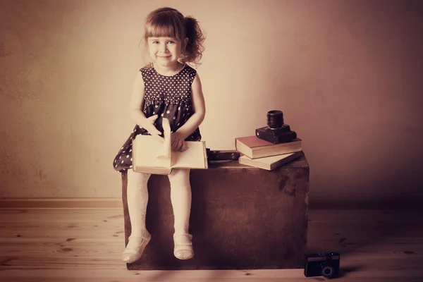 Malá holčička, čtení knihy na starý kufr — Stock fotografie