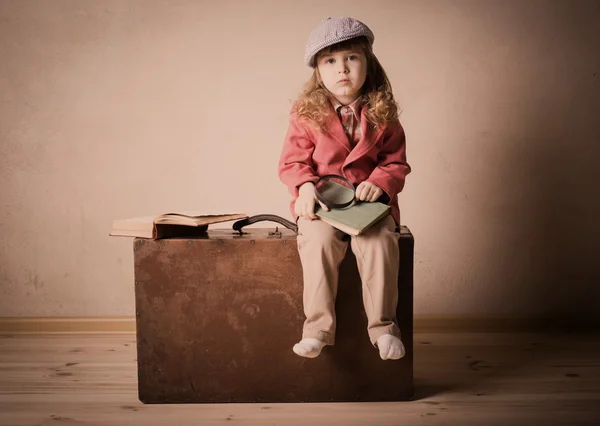 Little child with book on suitcase indoor — Stock Photo, Image