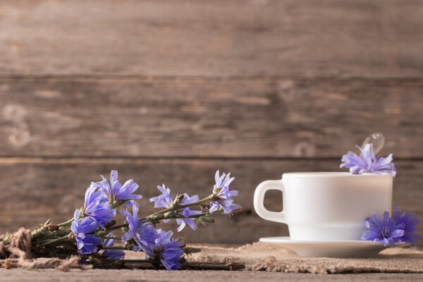 Cup of tea with chicory on wooden background