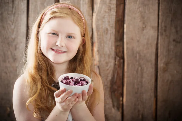 Gelukkig meisje met dessert op houten achtergrond — Stockfoto