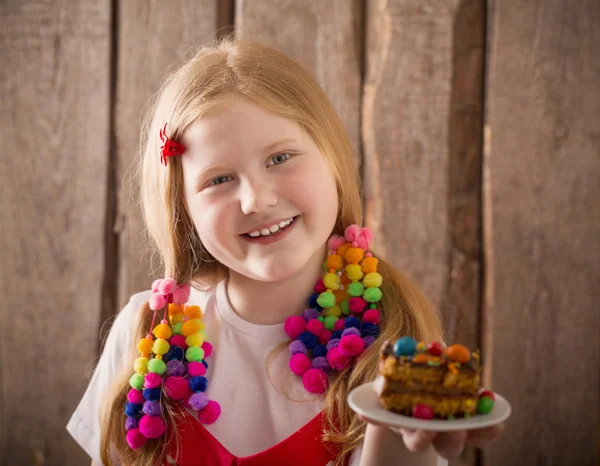 Smile girl with cake on wooden background — Stock Photo, Image