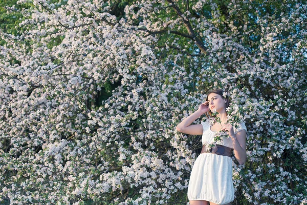 Schöne junge Mädchen auf Hintergrund blühenden Apfelbaum — Stockfoto