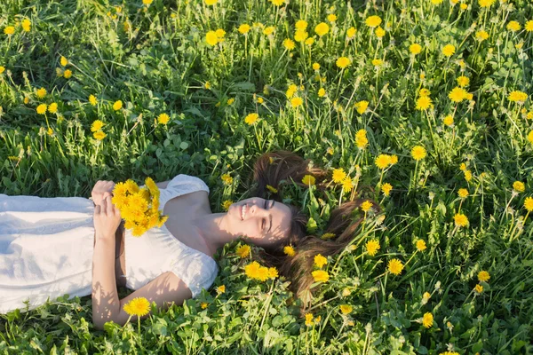 Vackra flicka är avkopplande liggande i gräset i trädgården — Stockfoto