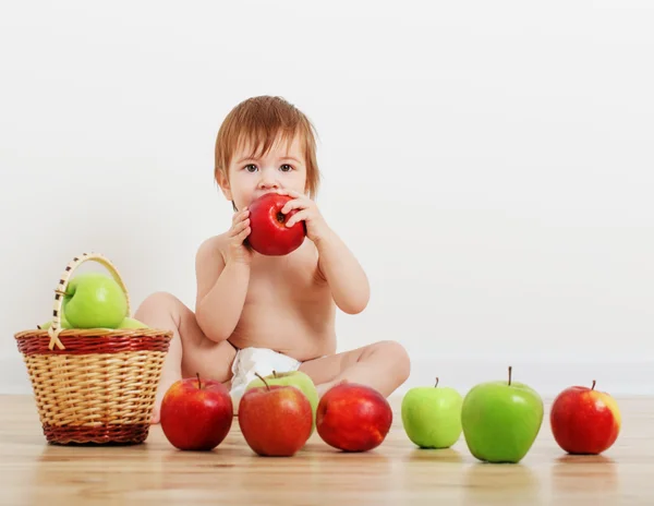 Retrato de uma criança pequena bonito com maçãs interior — Fotografia de Stock