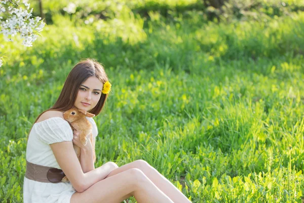 Schöne junge Frau mit Kaninchen im Garten — Stockfoto