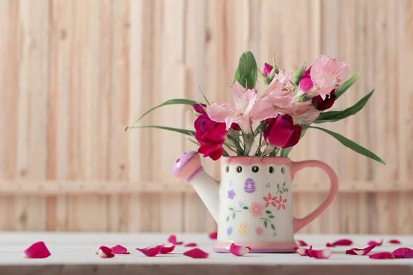 Bouquet of bright flowers in watering can on wooden background — Stock Photo, Image