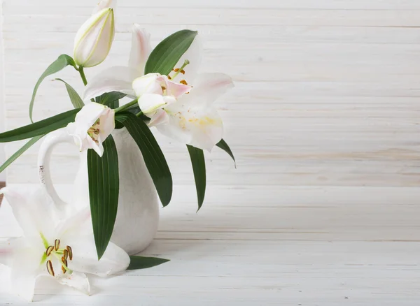 Lily in jug on white wooden background — Stock Photo, Image