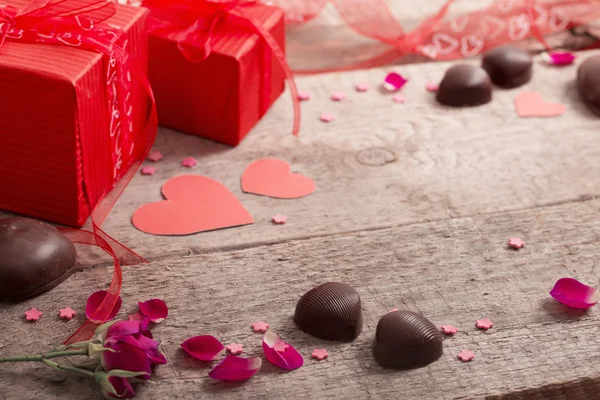 Valentinstag-Geschenkbox und rote Herzformen auf Holzbrett — Stockfoto