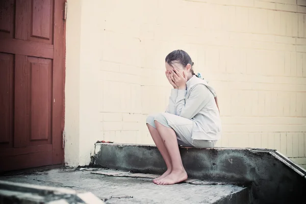 Portret smutny dziewczyna siedzi w pobliżu ściany — Zdjęcie stockowe