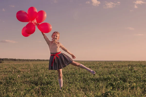 Gelukkig meisje met rode ballonnen buiten — Stockfoto