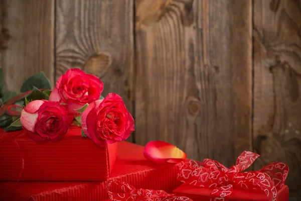 Caixa de presente vermelho e buquê de rosas em fundo de madeira — Fotografia de Stock