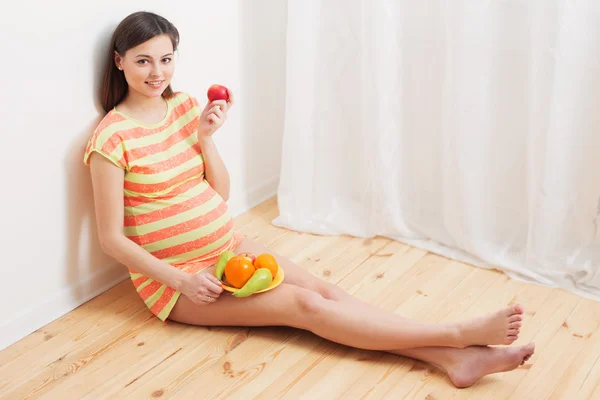 Беременная женщина ест фрукты — стоковое фото