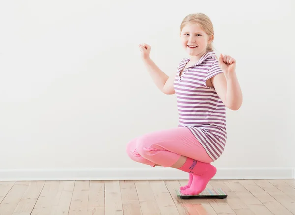 Happy girl  on scales indoor — Stock Photo, Image