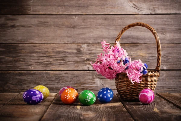 Uova di Pasqua in cesto su sfondo di legno — Foto Stock