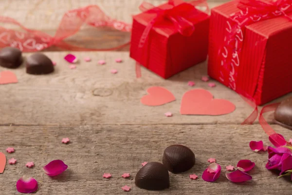 Valentine caixa de presente e formas de coração vermelho na placa de madeira — Fotografia de Stock