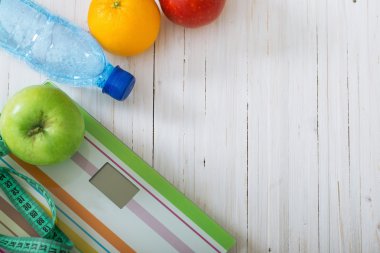 Ölçekler, meyve, su beyaz ahşap zemin üzerinde