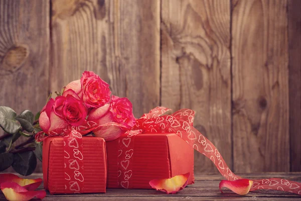 Caja de regalo roja y ramo de rosas sobre fondo de madera —  Fotos de Stock