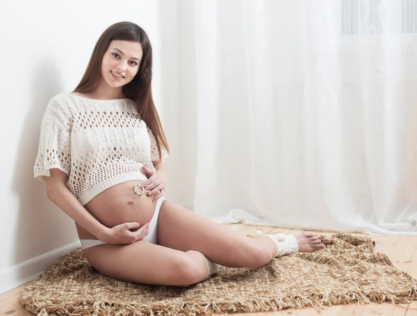 Feliz embarazo sentado en el suelo en casa — Foto de Stock