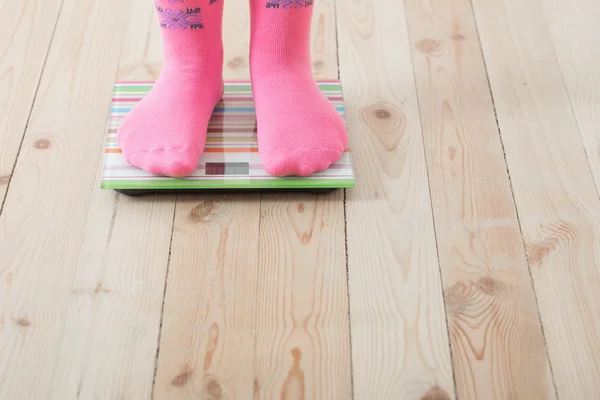 Feet on scales on wooden floor — Stock Photo, Image