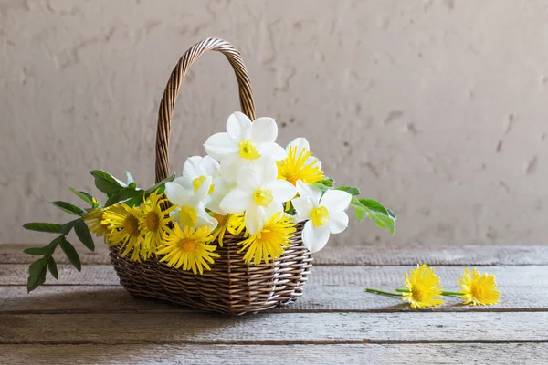 Frühlingsblumen im Korb auf hölzernem Hintergrund — Stockfoto