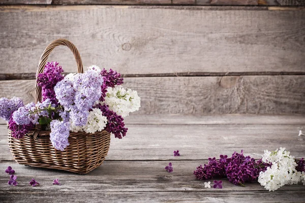 Cesto con un ramo di fiore lilla su fondo di legno — Foto Stock