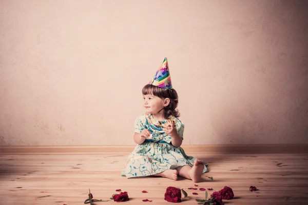 Little girl eating cake in a festive cap in vintage style — Stock Photo, Image
