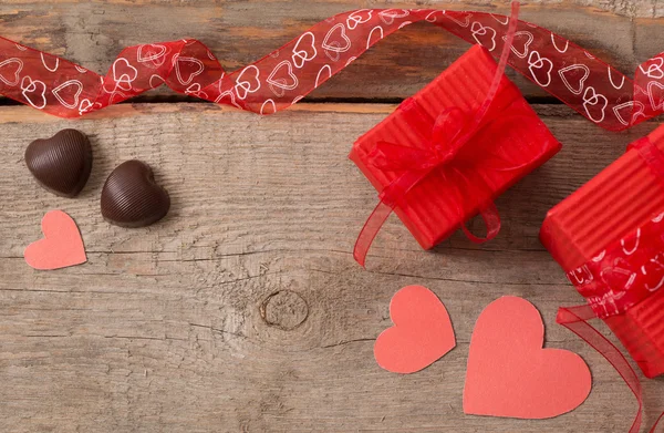 Valentine caixa de presente e formas de coração vermelho na placa de madeira — Fotografia de Stock