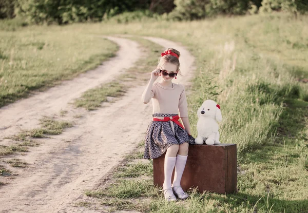 Beautiful girl on suitcase with red balloons outdoor — Stock Photo, Image