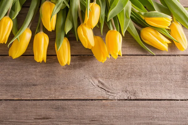 yellow tulips over wooden table background