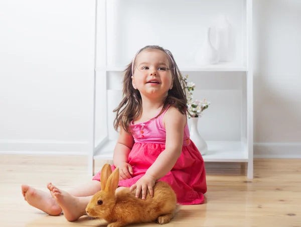 Маленькая девочка с кроликом в помещении — стоковое фото