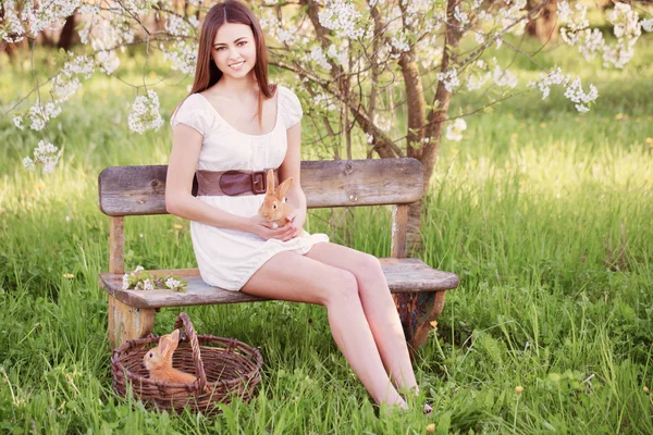 Hermosa joven con conejos en el jardín — Foto de Stock